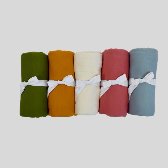 Rolled view of the Merino Baby Wrap in colours Avocado, Marigold, Cream, Guava and Duck Egg